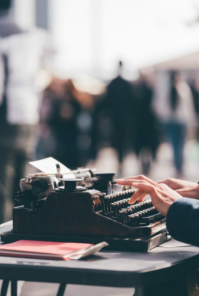 hands typing on a black manual typewriter